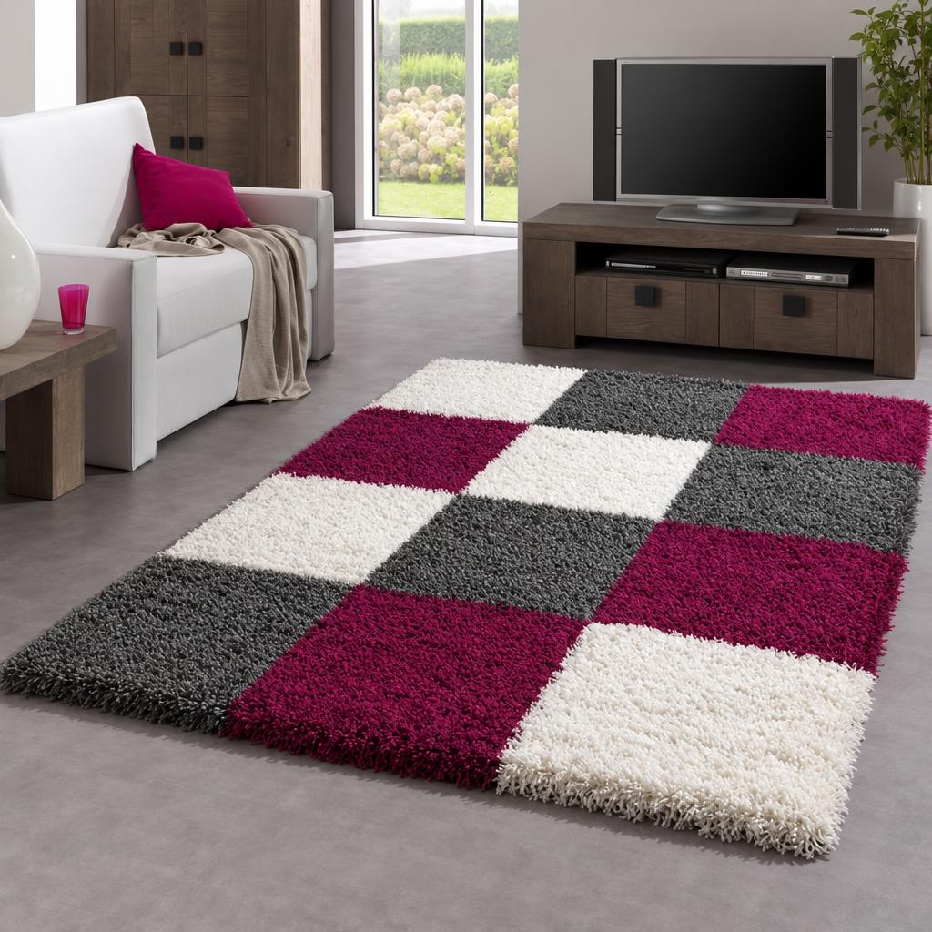 Vloerkleed Shaggy Plus 910 Purple, hoogpolig met blokken in paars, antraciet en wit, naast een witte bank – sfeerimpressie in de woonkamer