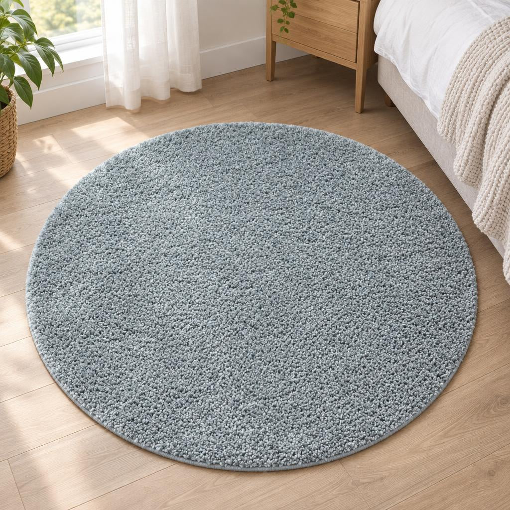 Rond hoogpolig vloerkleed Shaggy Ritual Turquoise in zacht grijsblauw, naast het bed – sfeerimpressie in de slaapkamer