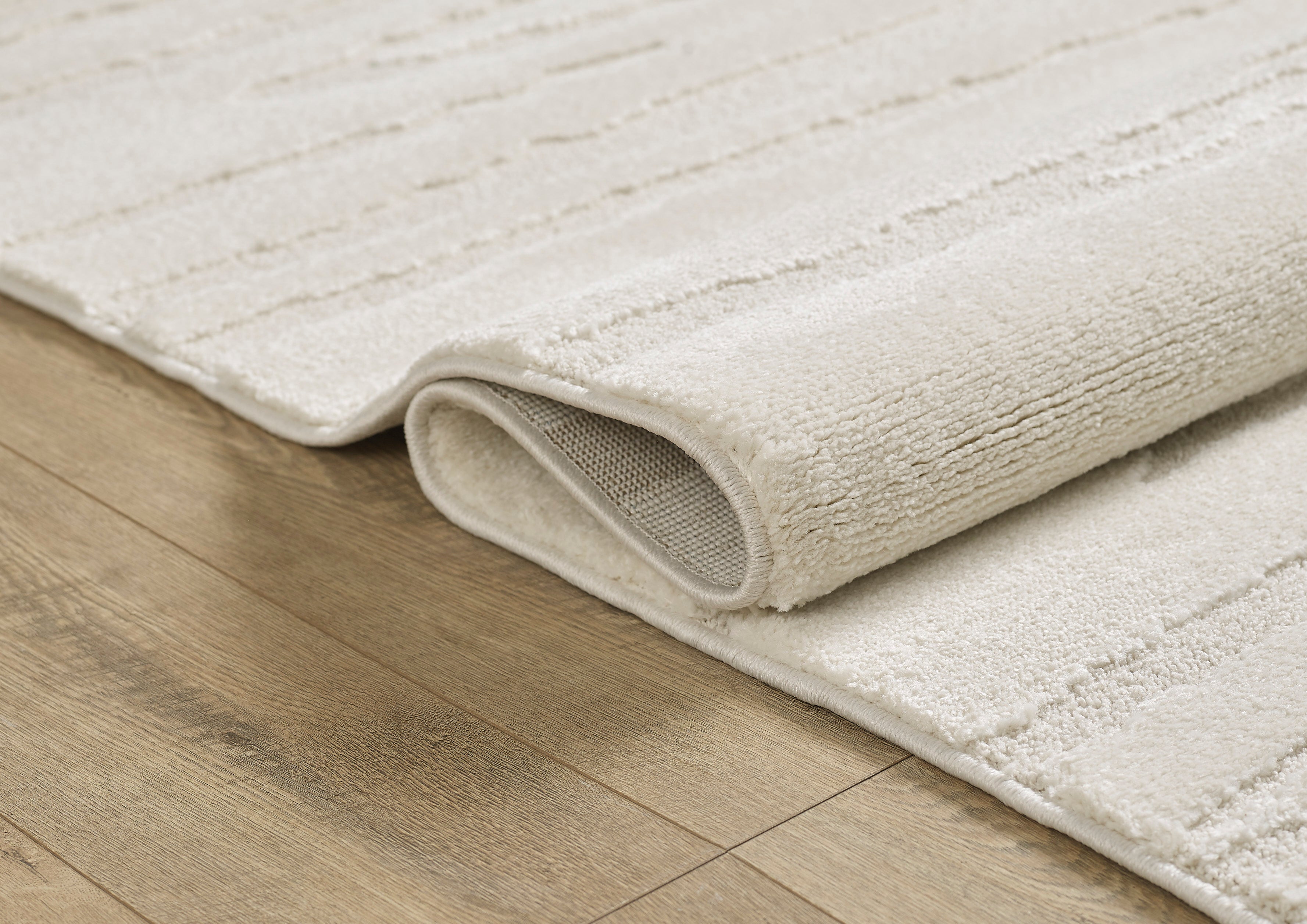 Vloerkleed Elio 2257 Crème – Rustig laagpolig met dichte pool – opgerolde hoek met jute rugzijde