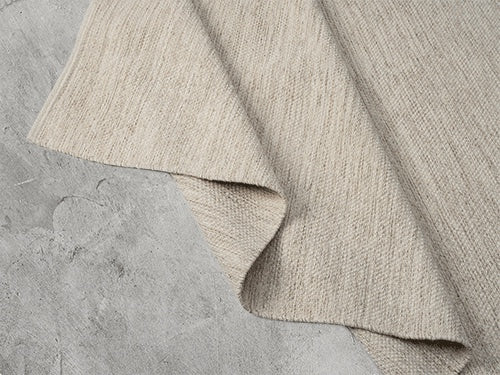 Vloerkleed Stockholm Crèmebeige – Geweven Wol met Katoen – hoek van het kleed op een houten vloer