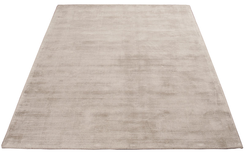 Vloerkleed Arte Lichtbeige – Viscose pool met warme uitstraling – opgerolde hoek op een houten vloer