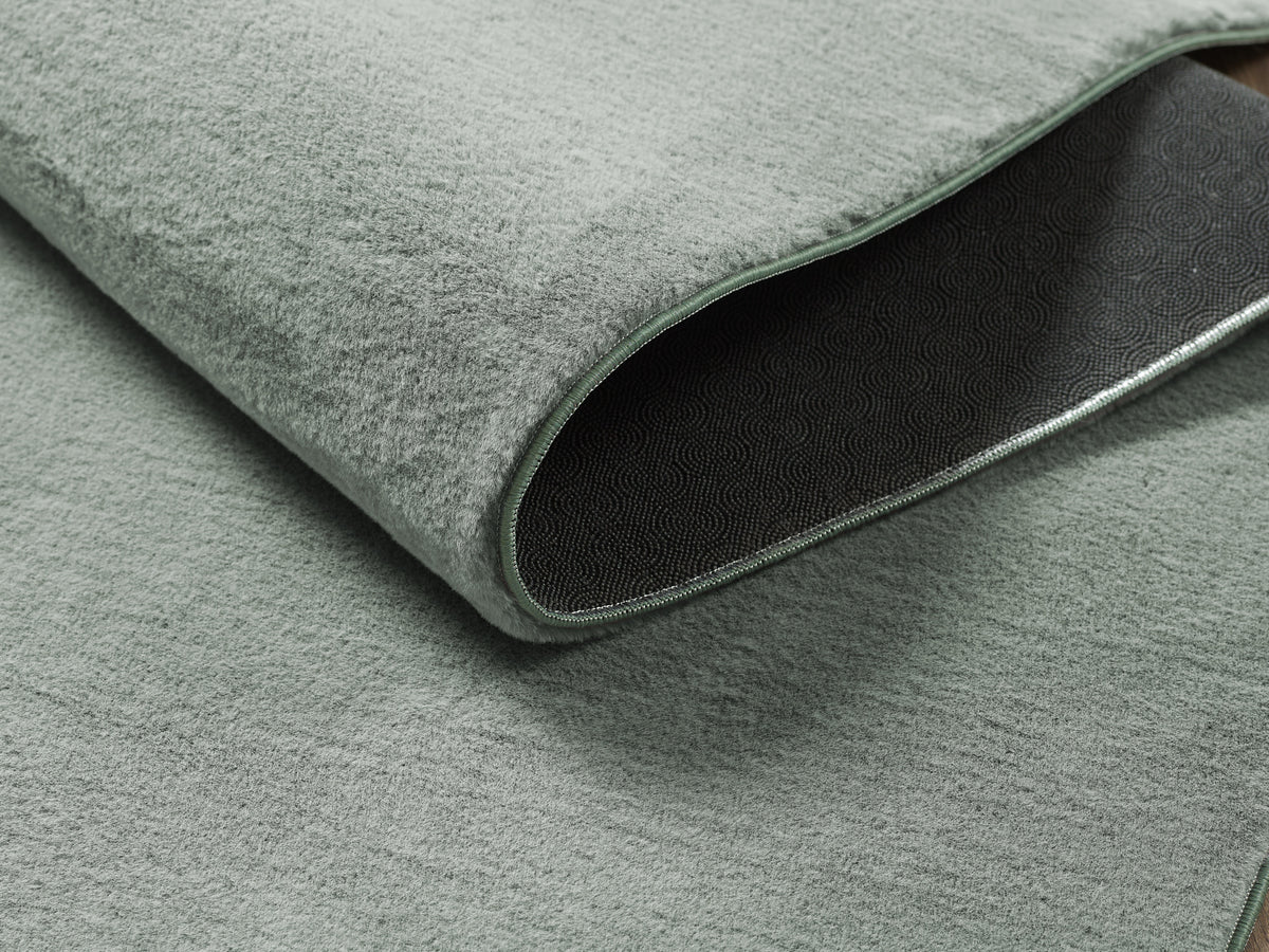 Vloerkleed Cozy Groen – Laagpolig geweven kleed met korte pool – opgerolde hoek op een houten vloer