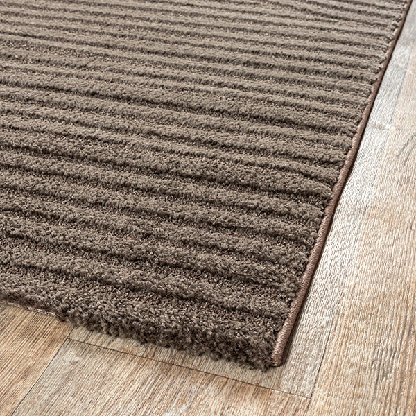 Vloerkleed Elio 2251 Bruin – Warm laagpolig geweven vloerkleed – sfeerimpressie bij een fauteuil