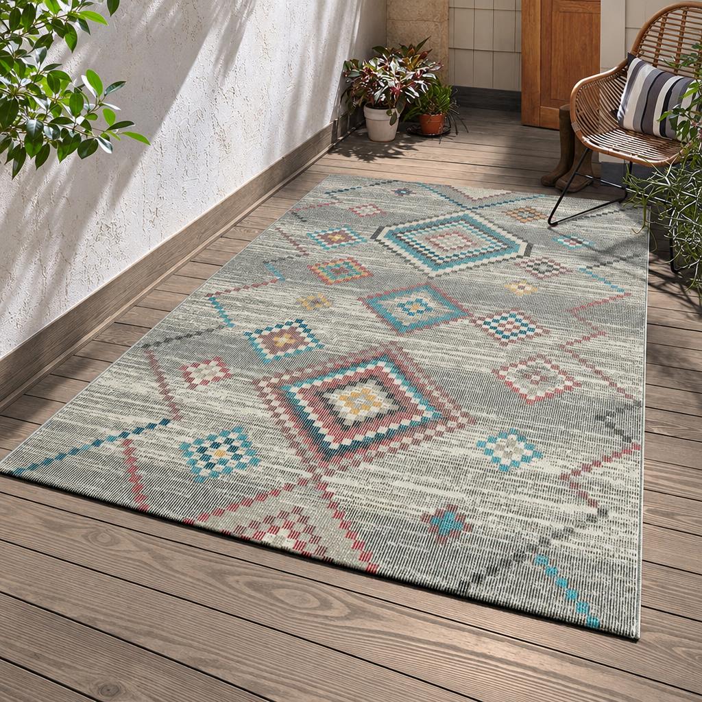 Karpet24 Salsa binnen- en buitenkleed in grijs met Aztec-ruiten in blauw, roze en oker op een overdekte houten veranda