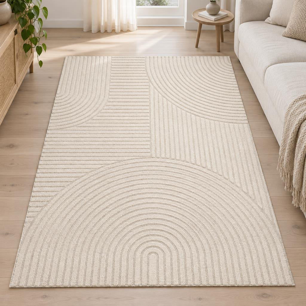 Vloerkleed Elio 2252 Beige met boog- en lijnenreliëf naast een lichte bank – sfeerimpressie in de woonkamer