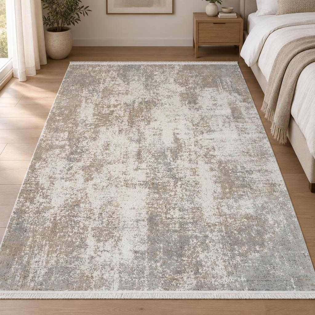 Vloerkleed Fabia Beige 70 met verweerd abstract dessin in ivoor, grijs en zand naast het bed – sfeerimpressie in de slaapkamer