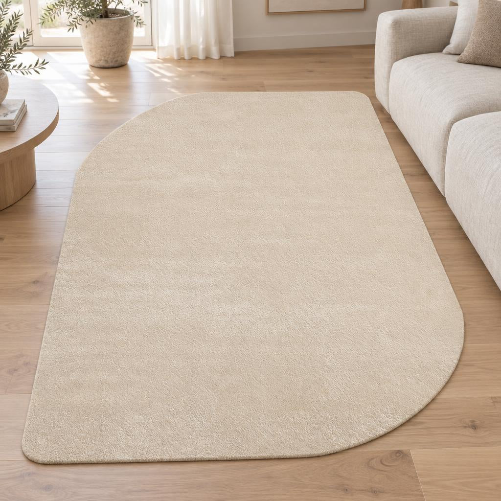 Vloerkleed Loft Shape 46 Beige in organische vorm, effen zandbeige, naast een linnen bank – sfeerimpressie in de woonkamer