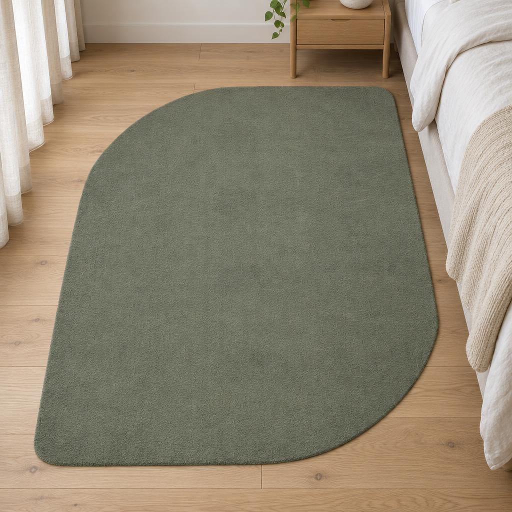 Vloerkleed Loft Shape 46 Bosgroen in organische bladvorm naast het bed op een eiken vloer – sfeerimpressie in de slaapkamer