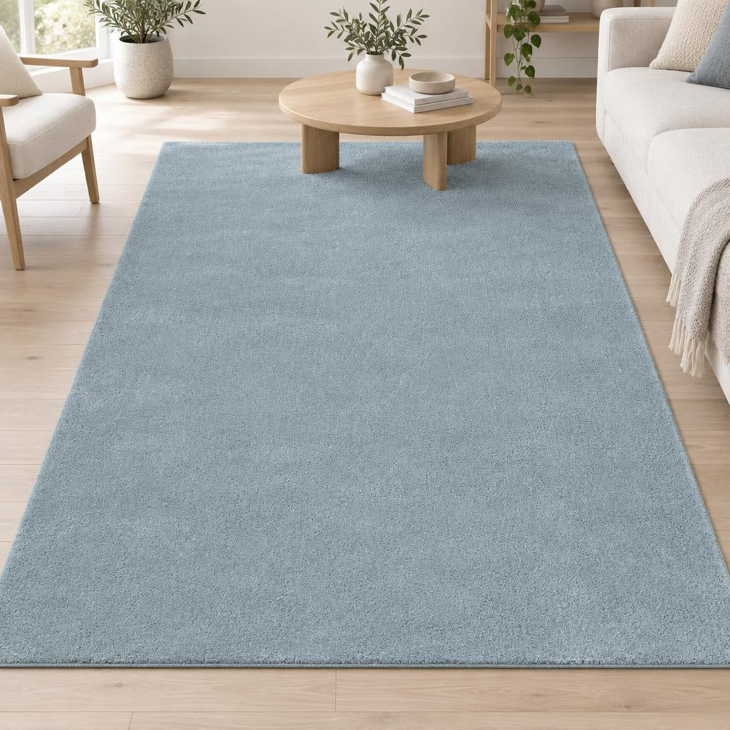 Vloerkleed Loft Washable Blauw, effen grijsblauw en wasbaar, met een ronde eiken salontafel – sfeerimpressie in de woonkamer