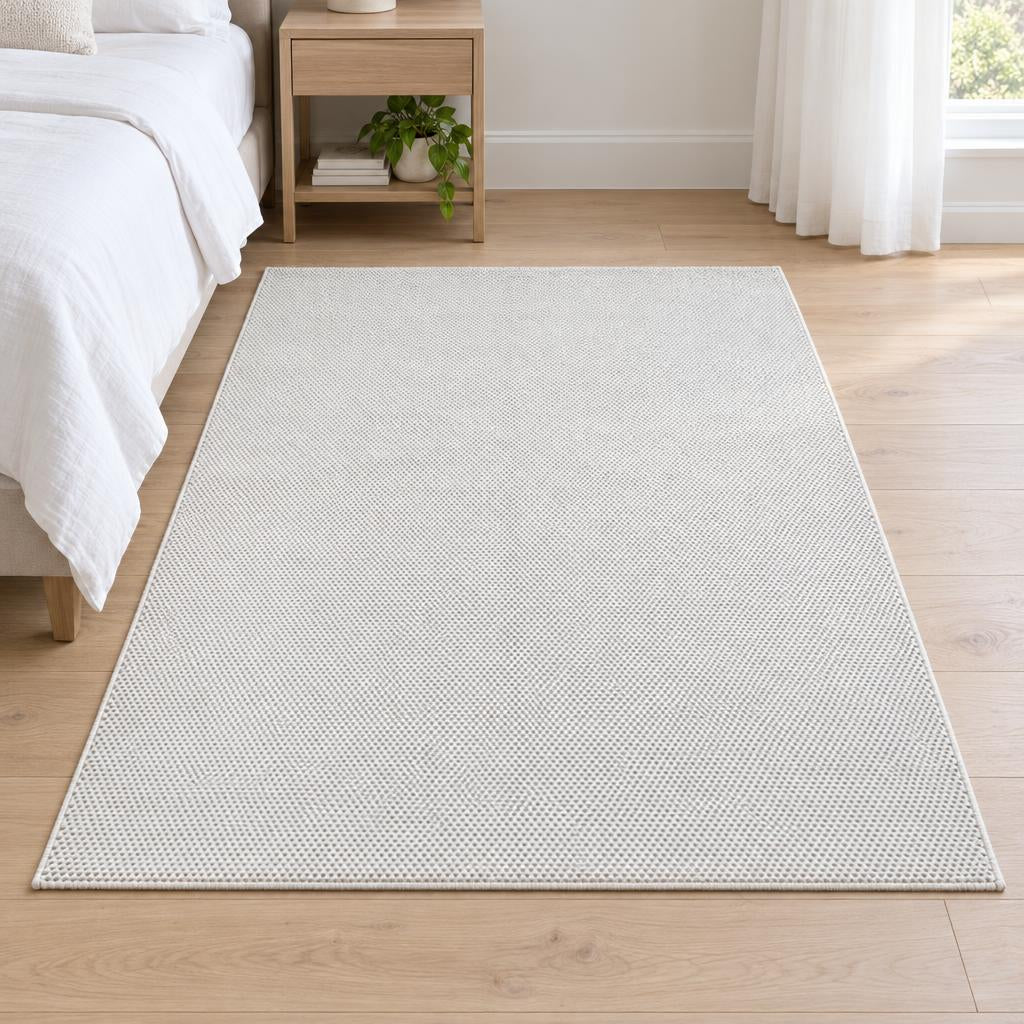 Vloerkleed Mira 7506 Crème, laagpolig met fijne geweven noppenstructuur, naast het bed – sfeerimpressie in de slaapkamer