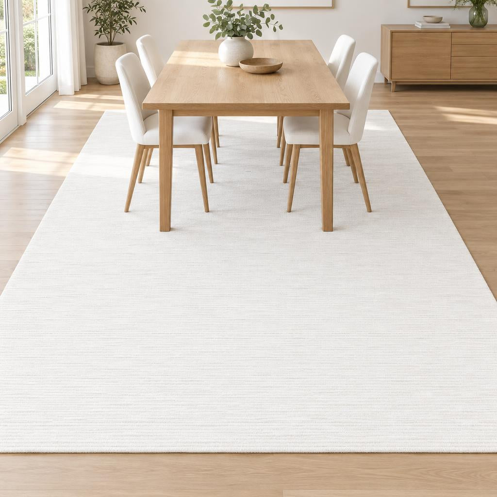 Effen vloerkleed Nepal 6404 Crème onder een eiken eettafel met witte stoelen – sfeerimpressie in de eetkamer