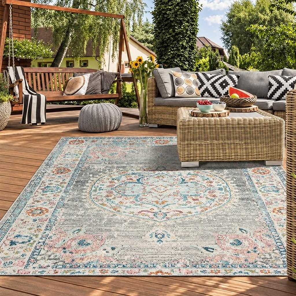 Vloerkleed Salsa Grijs met vintage medaillon en roze bloemen onder een rotan salontafel – sfeerimpressie op het terras