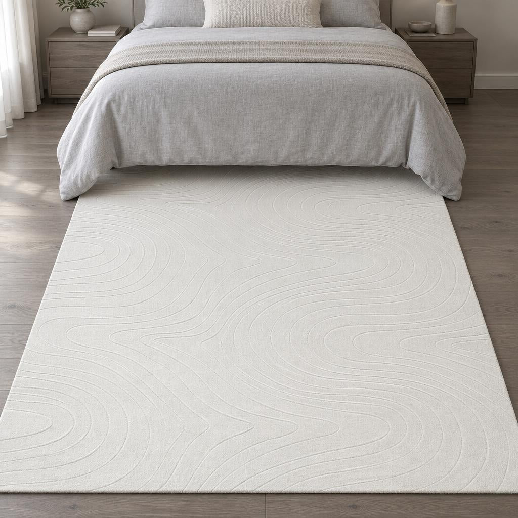 Vloerkleed Stilo 397 Crème met golvend lijnenreliëf aan het voeteneind van het bed – sfeerimpressie in de slaapkamer